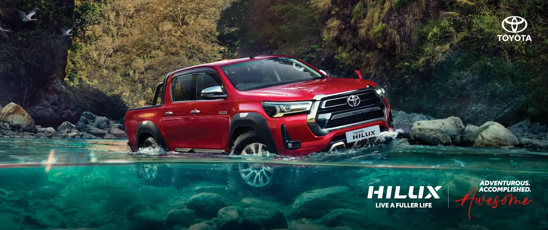 Toyota Hilux pickup truck driving through rocky terrain